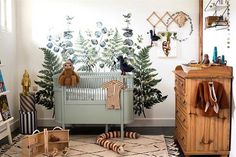 a baby's room decorated in neutral tones and greenery, with toys on the floor