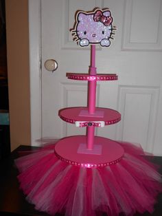 a hello kitty birthday cake stand with pink tulle skirt and bow on the top