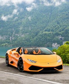 an orange sports car parked in front of a mountain