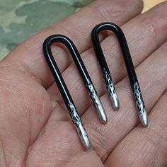 pair of black and silver metal ear clips in the palm of someone's hand