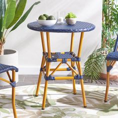 two chairs and a table in front of a potted plant