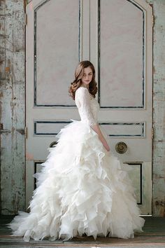 a woman in a white wedding dress standing by a door