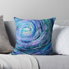 a blue and purple swirl pillow sitting on top of a gray couch next to pillows