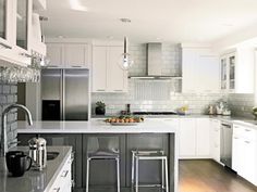 a large kitchen with white cabinets and stainless steel appliances