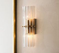 a wall light that is mounted to the side of a wall next to a mirror