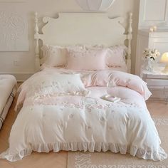 a white bed with pink comforter and pillows