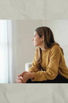 a woman sitting on a couch looking out the window