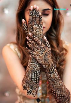 a woman holding her hands up with henna on it