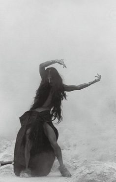 a woman with long hair is standing in the snow holding her arms out and looking at something