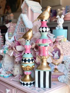 a pink dresser topped with lots of colorful vases and birds on top of it