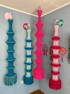 three colorful vases are hanging on the wall with tassels attached to them