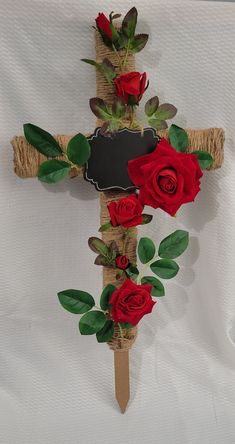 a cross decorated with red roses on a white table cloth and burlock for decoration