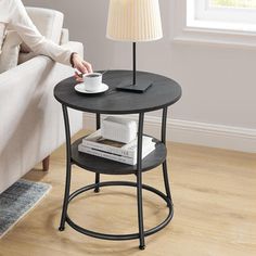 a woman sitting on a couch next to a table with a coffee cup on it