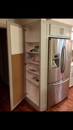 a stainless steel refrigerator and freezer combo in a kitchen with hardwood floors, white cabinets and wood flooring