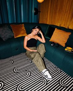 a woman sitting on top of a green couch in a living room next to pillows