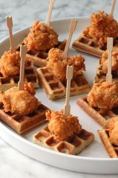 chicken and waffles are served with toothpicks on a white platter