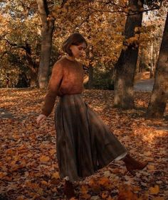 a woman is walking through leaves in the woods