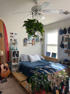 a bedroom with a bed, plant and guitar