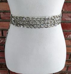 This is a vintage chain belt in silver metal with three rows of connected chains in the front decorated with large round clear rhinestones. There are also rhinestone links at the ends of the connected chains. It has a swivel hook closure with an adjusting chain and hanging chains and rhinestone charms on the end. The condition is excellent. Measurements: Total length 42 inches including charms at the end Adjustable from 32.5 to 35 inches Adjusting chain 3.5 inches Width 1.5 inches Price includes free shipping within the USA. Please visit my other Etsy shop for vintage jewelry: https://www.etsy.com/shop/BunnyLazuli Virtually everything we sell has been previously worn/used so it is likely to show some degree of evidence of that. There will be a note in the description if there is anything m Vintage Chain, Silver Belts, Chain Belt, Vintage Belts, Clear Rhinestones, Silver Metal, Chain Link, Metallic Silver, Belts