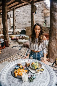 a woman sitting at a table with food in front of her on instagram page