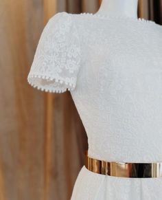 a white dress with gold belt on a mannequin