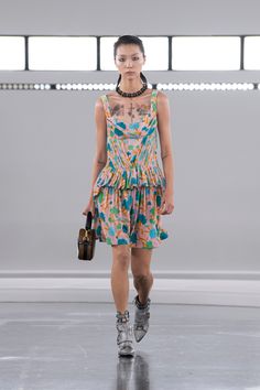 a model walks down the runway in a colorful dress