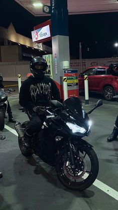 a man riding on the back of a black motorcycle in a parking lot at night