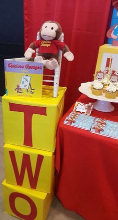 a table with cupcakes and a stuffed animal on it's chair next to a sign that says iwo