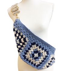 a crocheted blue and white purse on a mannequin headpiece,