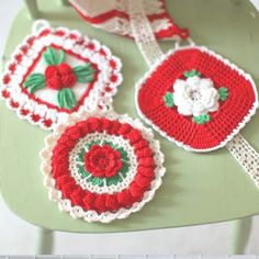 crocheted red and white coasters with flowers on them sitting on a green chair
