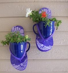 two blue vases with flowers in them hanging on a wall