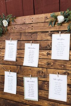 wedding seating chart hanging on wooden planks with flowers and greenery at the head table