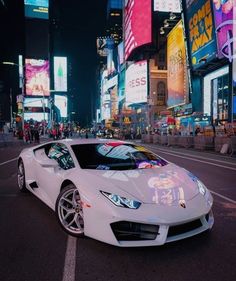 a white sports car parked on the side of a street in times square at night