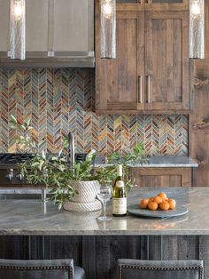 a kitchen counter with oranges and bottles on it, along with two chairs in front of the counter