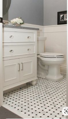 a white toilet sitting inside of a bathroom next to a black and white checkered floor