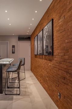 an empty kitchen with bar stools next to the counter top and brick wall behind it