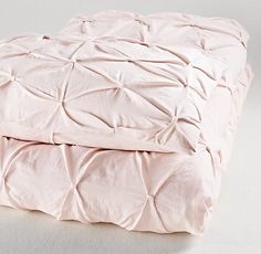 two pink bedspreads sitting next to each other on top of a white floor