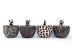 four ceramic pots with black and white designs on them