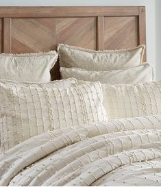 a bed with white sheets and pillows on top of it next to a wooden headboard