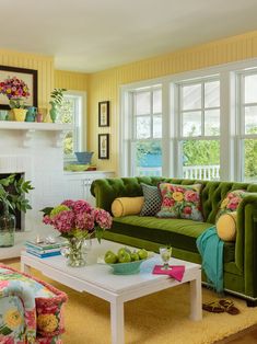 a living room filled with furniture and flowers on top of a table in front of a fire place