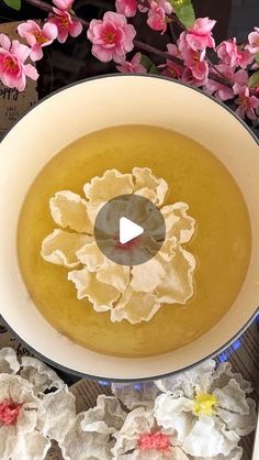 a bowl filled with soup next to pink flowers