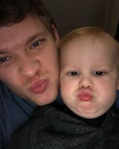 a man holding a baby in his arms and making a funny face at the camera