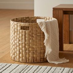a large woven basket sitting on top of a wooden floor next to a white rug