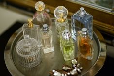 four different colored bottles on a silver tray with a mirror in the backround