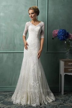 a woman in a white wedding dress standing next to a table with flowers on it