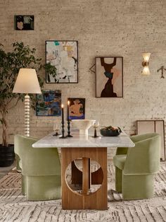 a dining table with green chairs and pictures on the wall