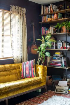 a living room filled with furniture and bookshelves next to a window covered in curtains