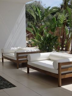 a white couch sitting on top of a tiled floor next to a green plant in a living room