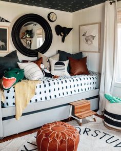 a bedroom with black and white decor on the walls, a round mirror above the bed