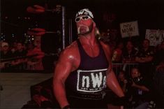 the wrestler is standing in front of a crowd with his hands on his hips and looking at the camera